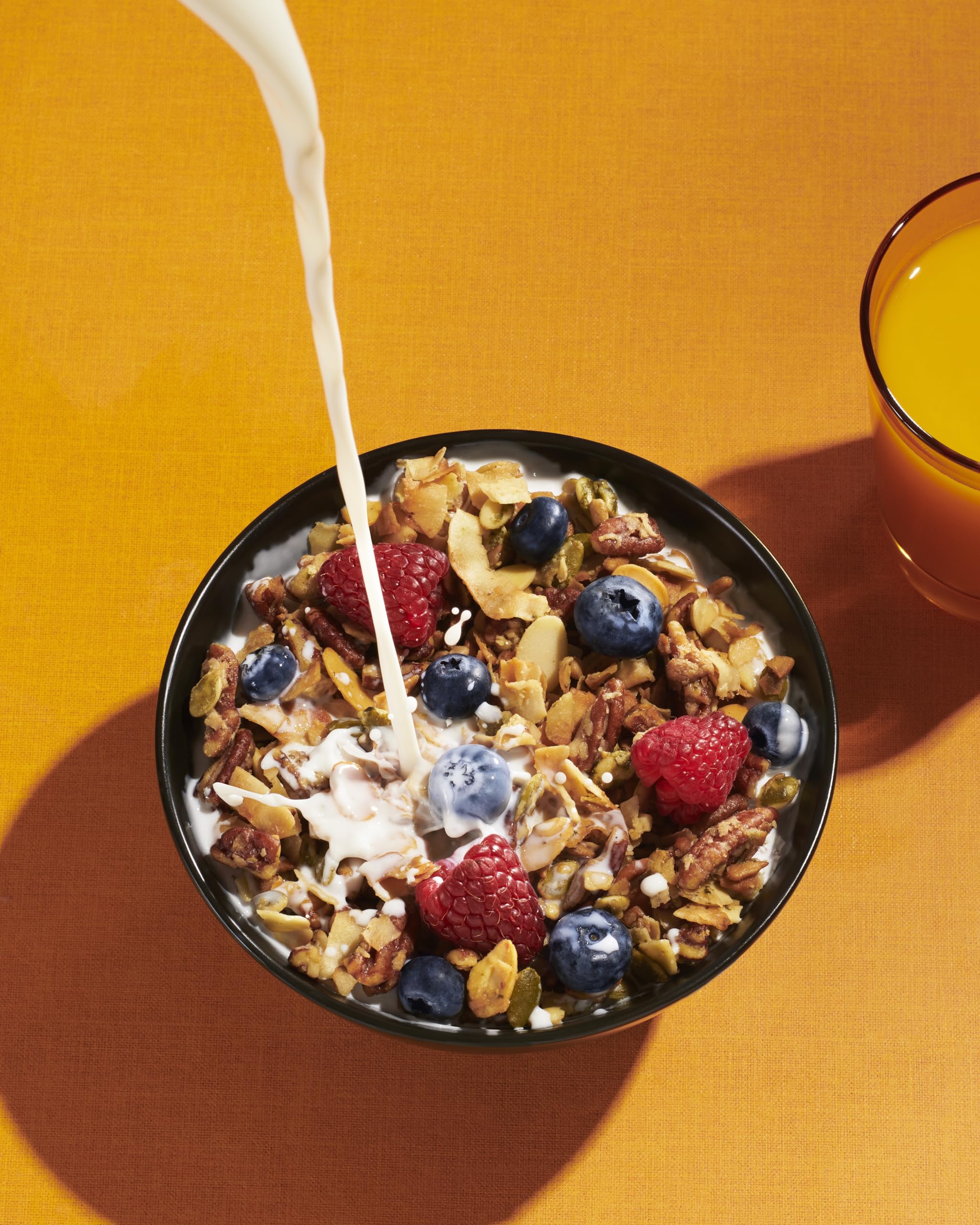 Pouring NuTrail granola into yogurt for a crunchy morning ritual.