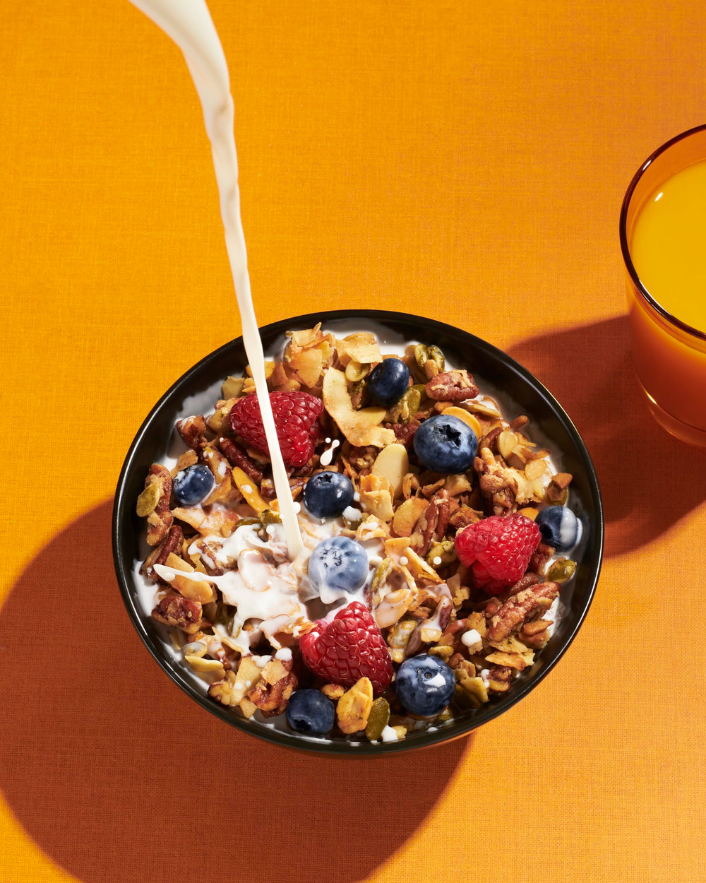 Pouring NuTrail granola into yogurt for a crunchy morning ritual.