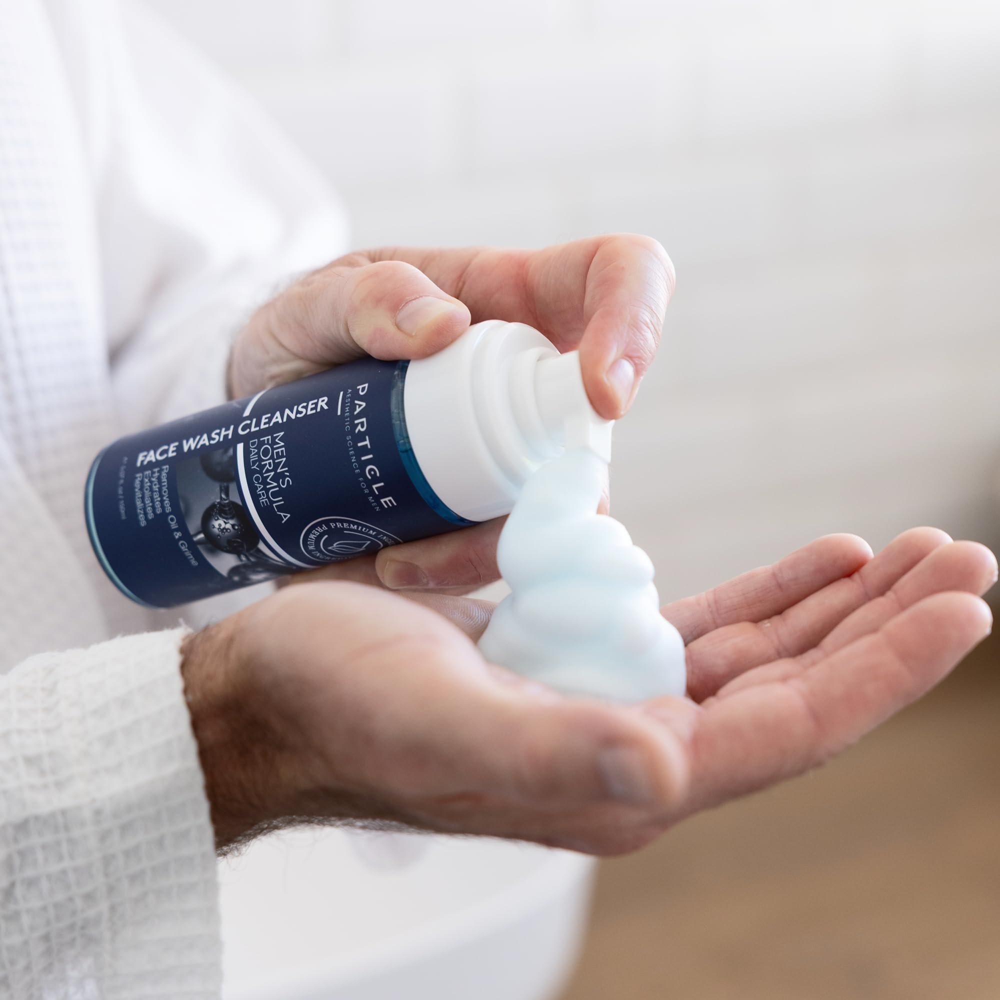 Hands applying Particle Face Wash and rinsing away impurities.