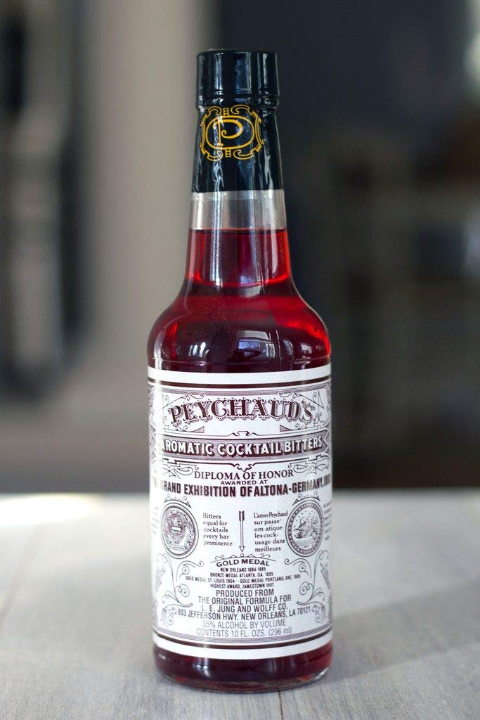 Peychaud's bottle with glass and ice demonstrates versatile use in cocktails.
