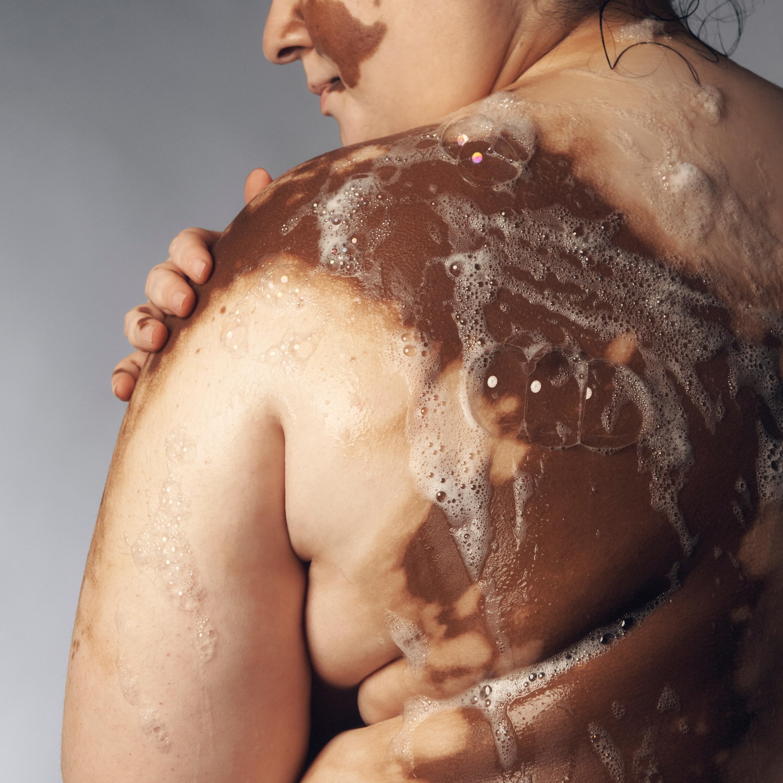 Philosophy Cinnamon Bun Bubble Bath under faucet evokes relaxing, fragrant soak.