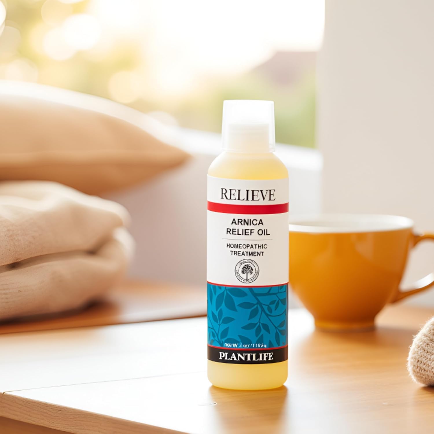 Closeup of Plantlife Arnica Relieve Oil bottle and drop.