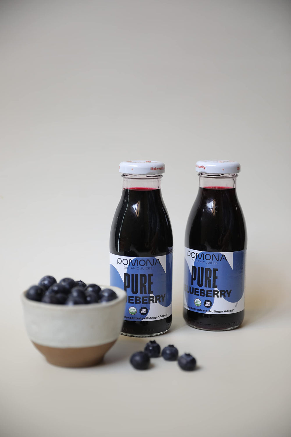 Pomona Blueberry Juice bottle on wood conveys natural, wholesome flavor appeal.