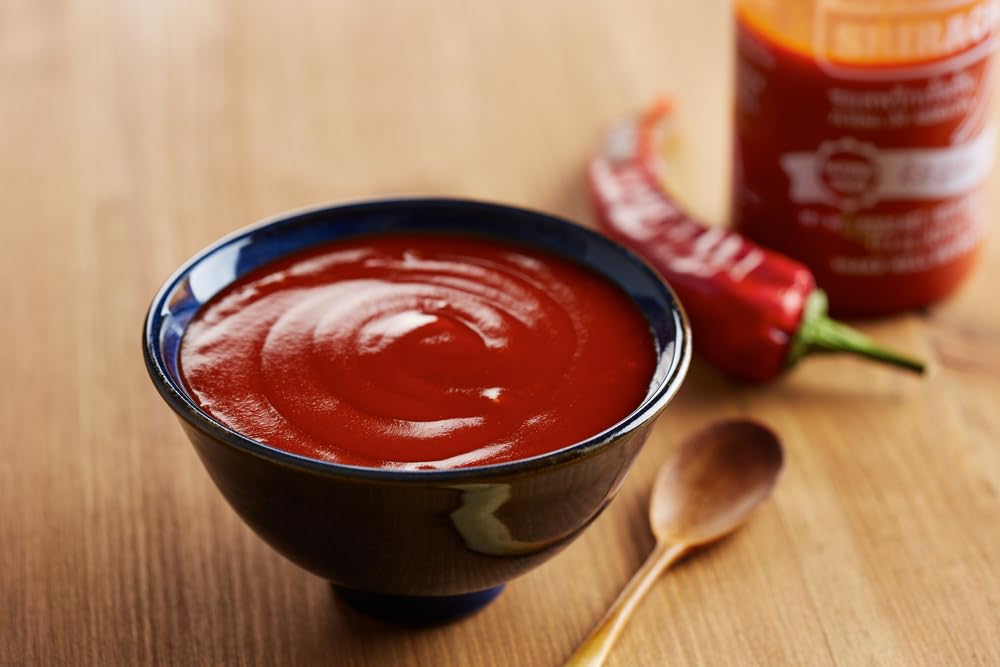 Rex Sriracha on a pizza slice highlights bold chili flavor.