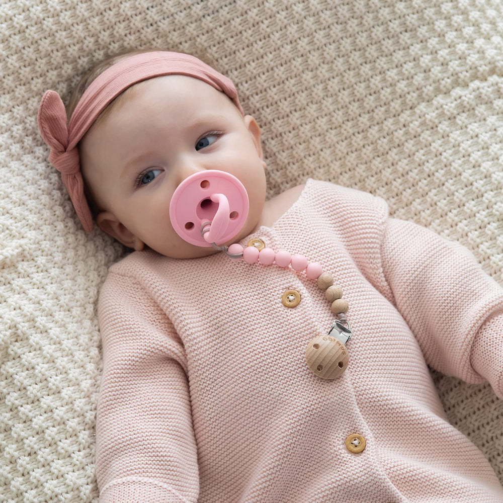 SAMiGO pacifier holder in coral-pink shows lightweight design for daily wear.