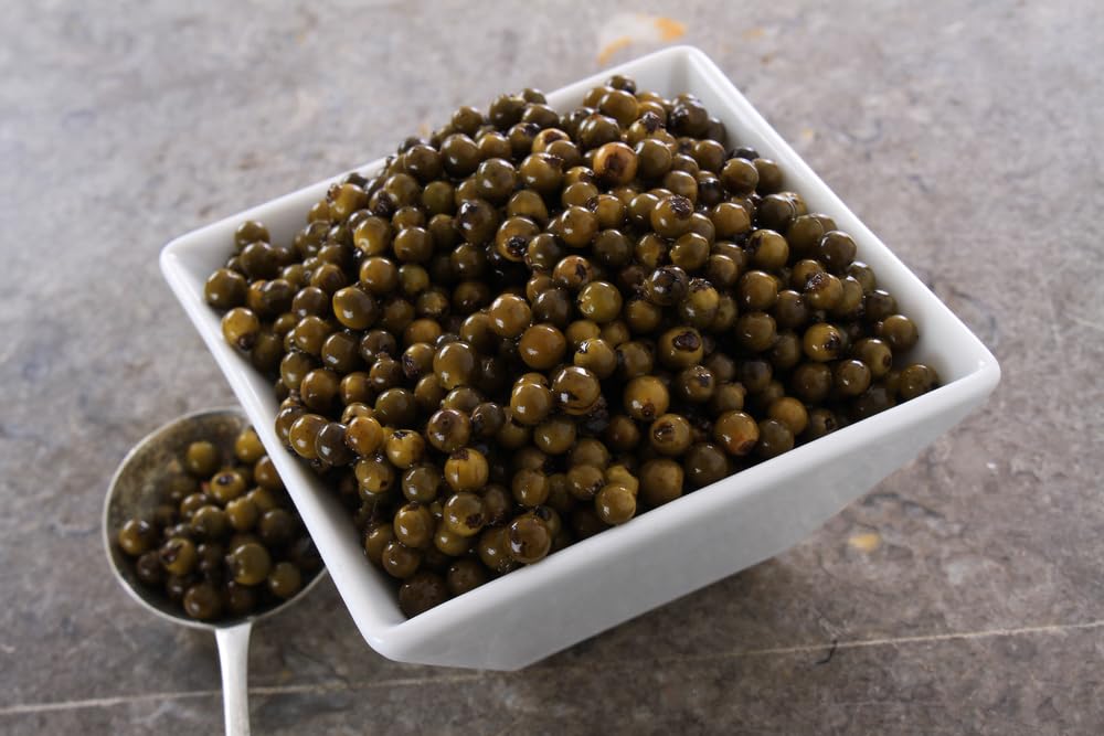 Two jars of Sanniti green peppercorns in brine on kitchen shelf.