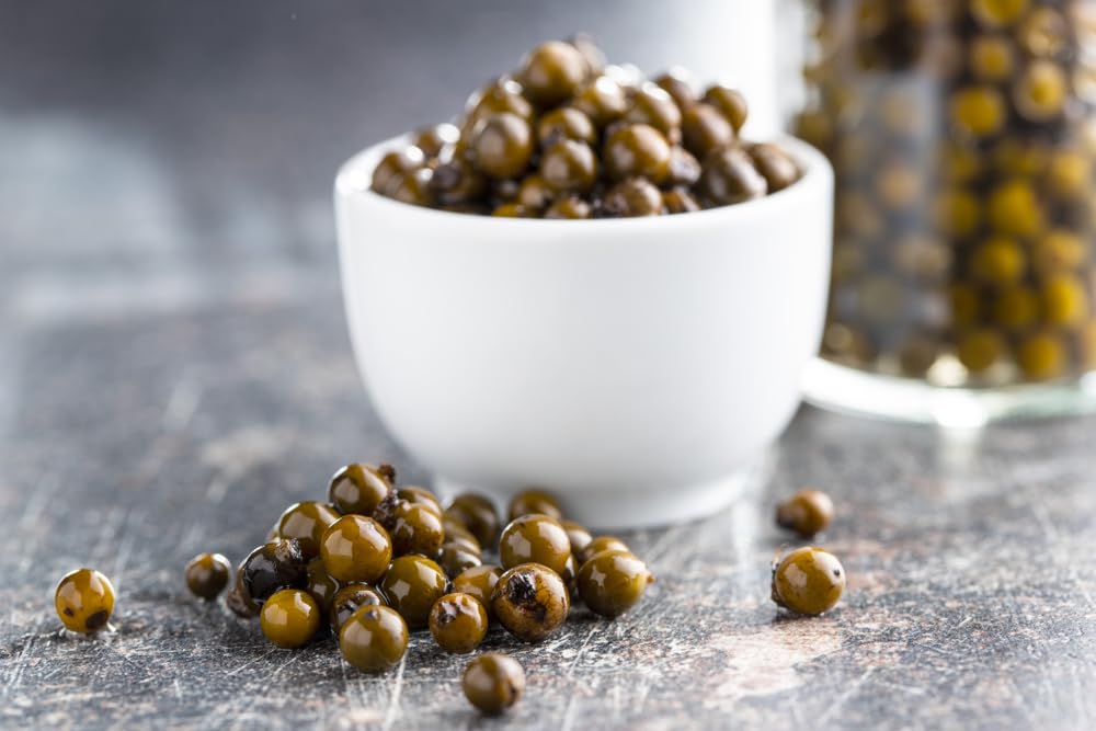 Sanniti peppercorns in brine with a plated meat dish.