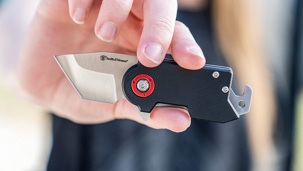 Tanto blade and bottle opener visible on Smith & Wesson Benji in outdoor setting.