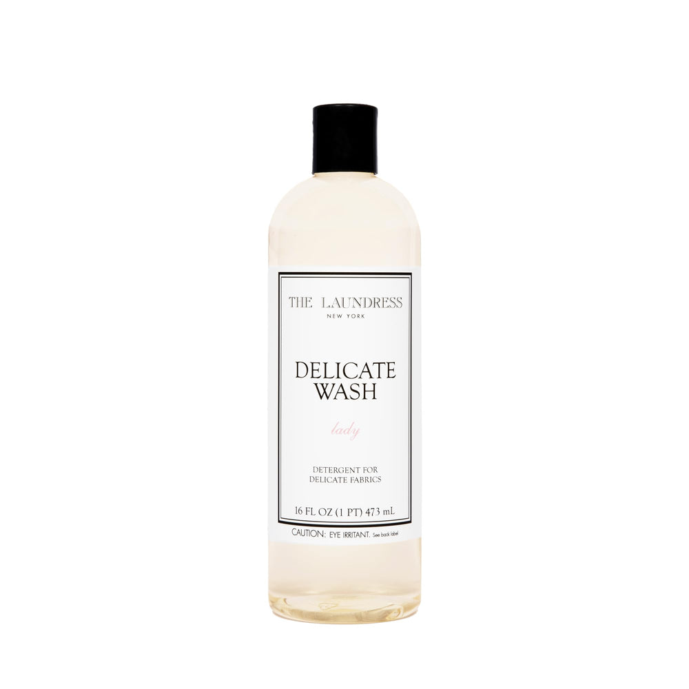 The Laundress Delicate Wash bottle pour demonstrates gentle, controlled dosing for delicate fabrics.