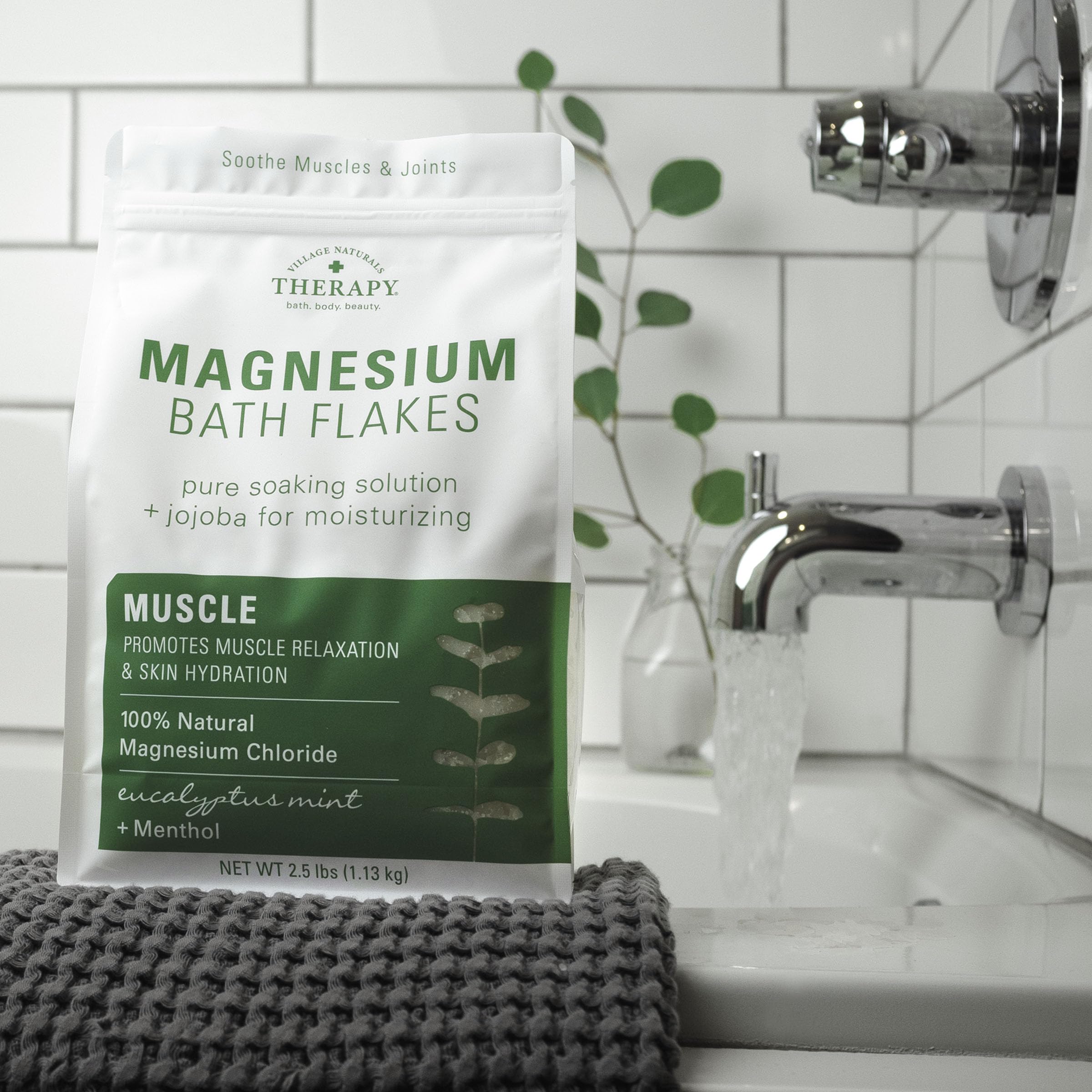 Village Naturals Therapy Muscle Magnesium Bath Flakes closeup in a jar highlighting natural minerals.